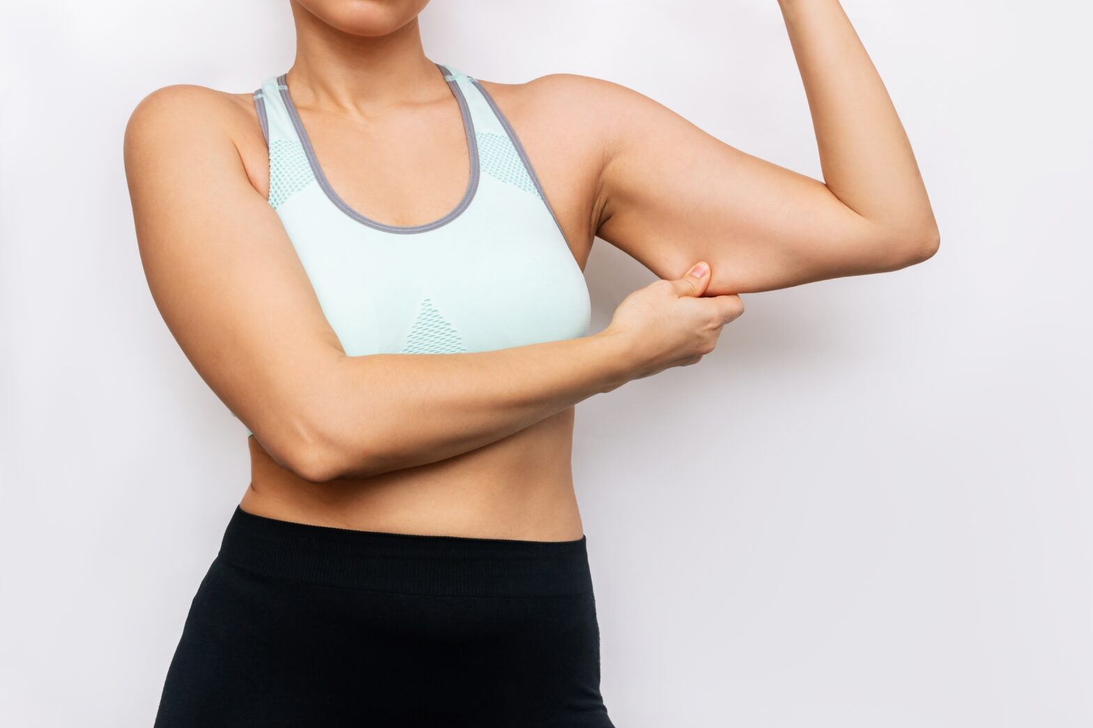 woman squeezing upper arm fat